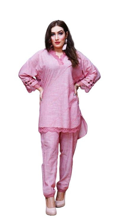 Woman wearing a pink traditional outfit standing in a room with a blue wall and black door.