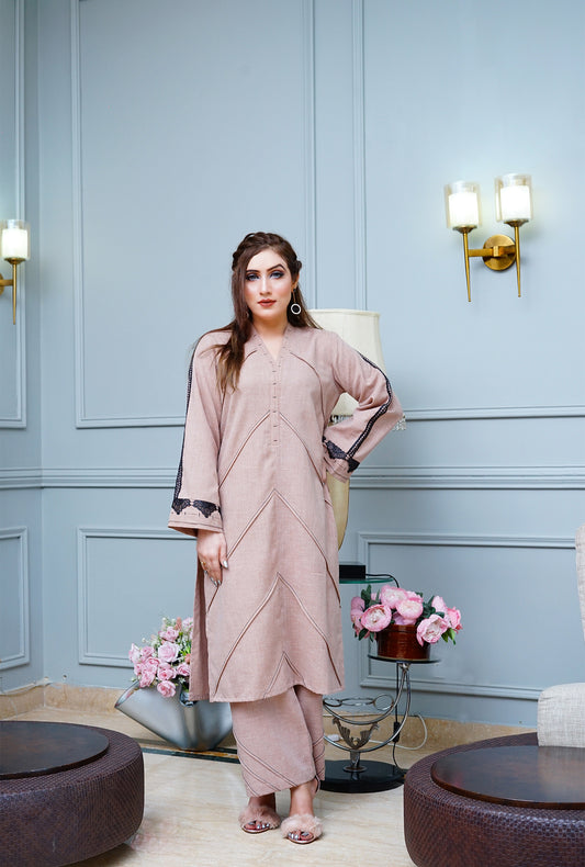 Shadow Shenaz woman in light brown pleated Irish linen kurta with black lace sleeves and matching salwar in sophisticated indoor setting