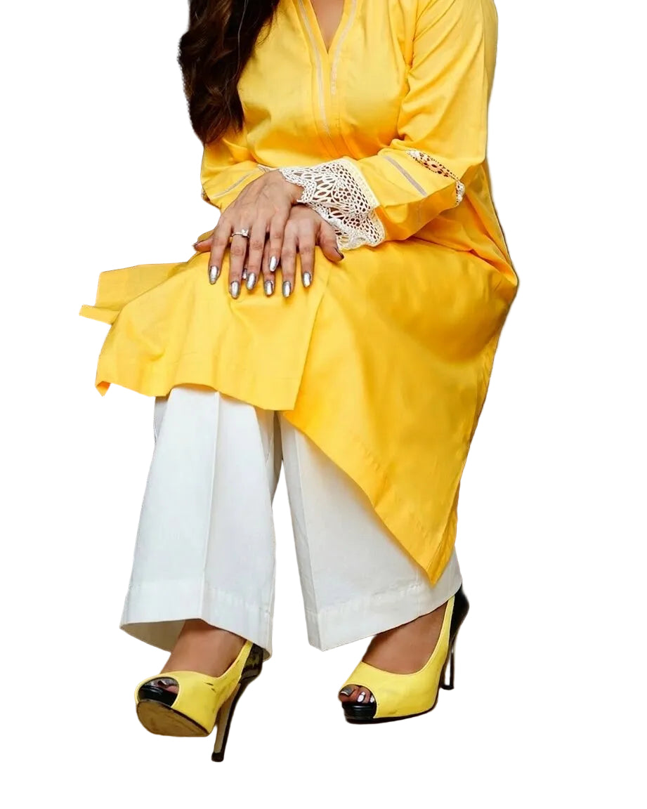 Person wearing a yellow outfit with white pants sitting on a chair.