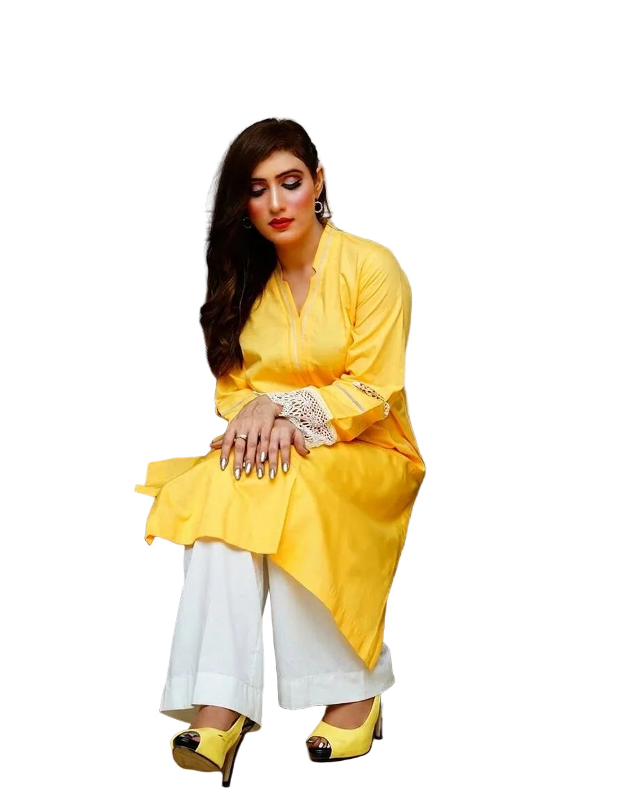 Woman in a yellow outfit sitting on a gray sofa in a room with a lamp and decorative pillows.